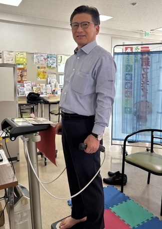 市長が体組成計に乗って、微笑んでいる写真